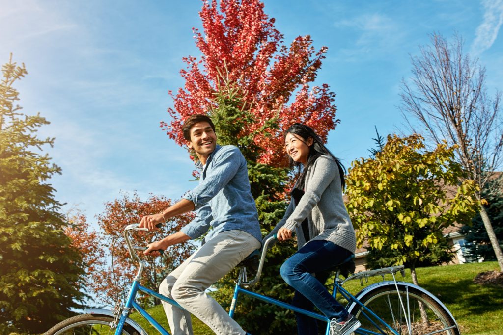 A man and a woman ride a tandem bicycle in the fall