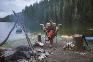 Woman completes a webcast while camping by the side of a lake