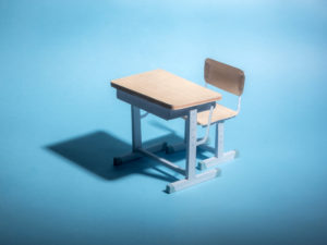 Empty school desk on a blue background. Conceptual.