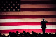 Man Standing On Stage Facing An American Flag