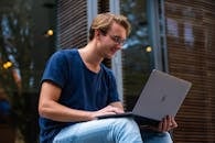 A young man sitting outdoors in Leiden, Netherlands, working on a laptop.