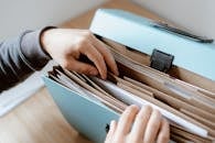 Close-up of hands organizing papers in a blue folder, ideal for business and office concepts.