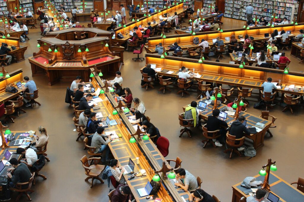 A lively university library scene with students studying diligently at wooden desks.