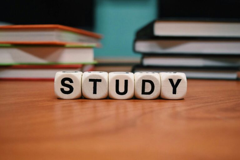 Close-up of study blocks and stacked books on a wooden desk, symbolizing education and learning.