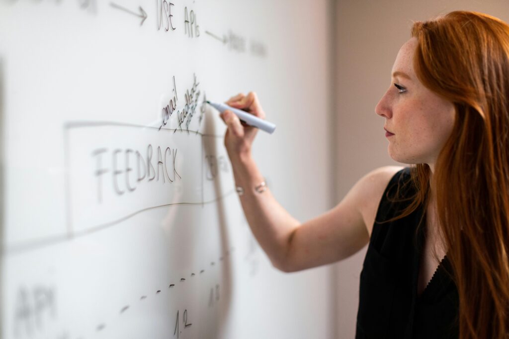 Focused woman writing on a whiteboard during a business planning session.