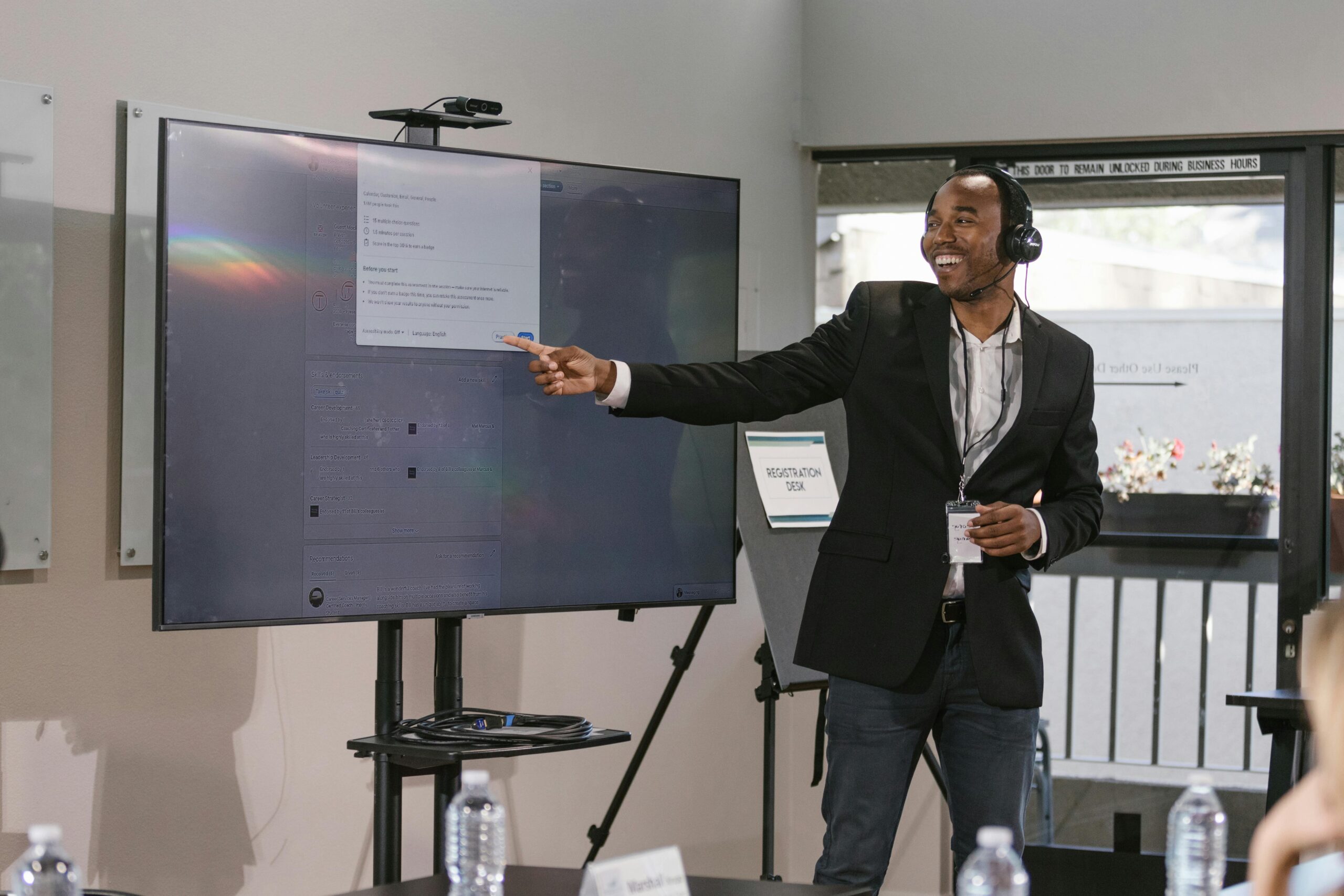 Business professional presenting with a digital screen, engaging an audience at a corporate event.