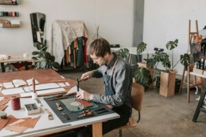 Leather craftsperson working at a table in a stylish workshop.